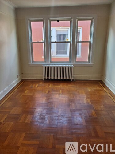 A room with wooden floors and a window with a view of a building outside.