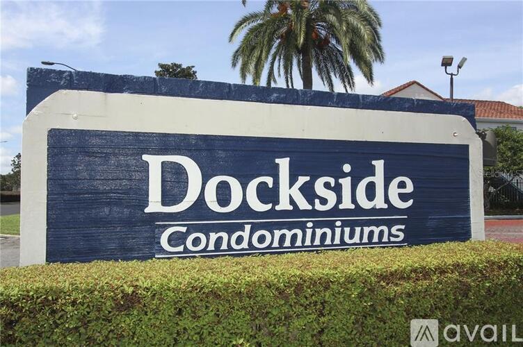 A sign for Dockside Condominiums is displayed in front of a hedge.
