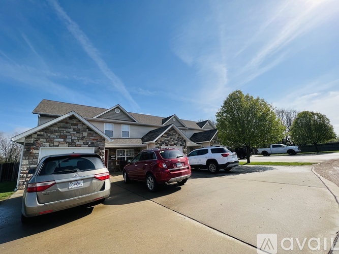 A house with a garage and two cars parked in front.