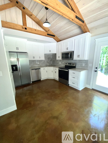 A kitchen with white cabinets and a wooden ceiling.