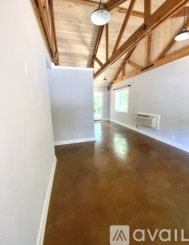 A room with wooden floors and a white wall with a window.