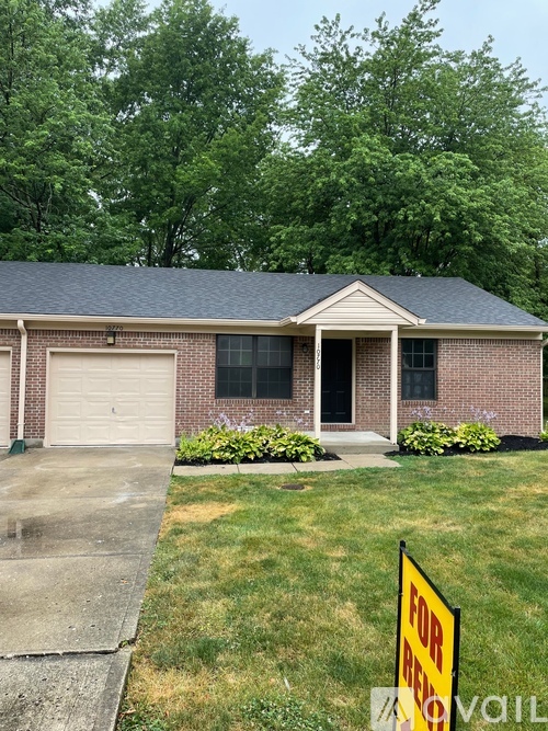 A house with a garage and a sign in front of it.