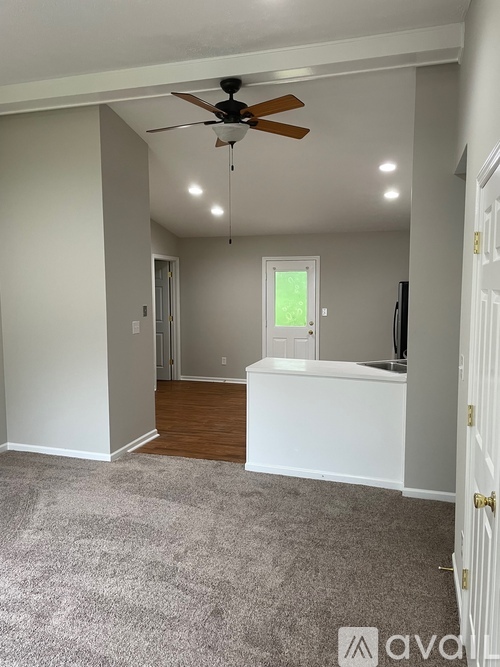 A room with a ceiling fan and carpeted floor.