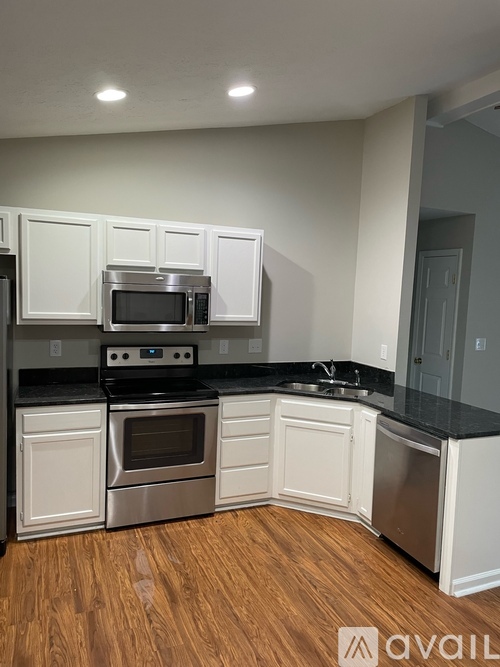 A kitchen with white cabinets and black countertops.