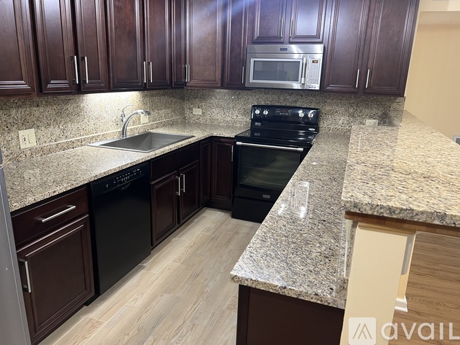 A kitchen with dark wood cabinets and granite countertops.
