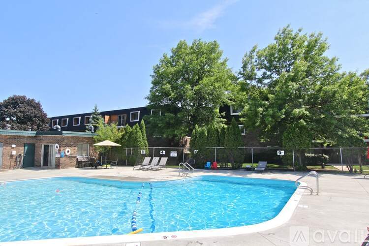 A large outdoor swimming pool surrounded by trees and a building in the background.