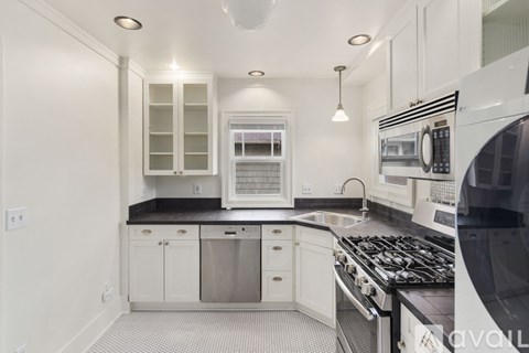 A modern kitchen with white cabinets and black countertops.