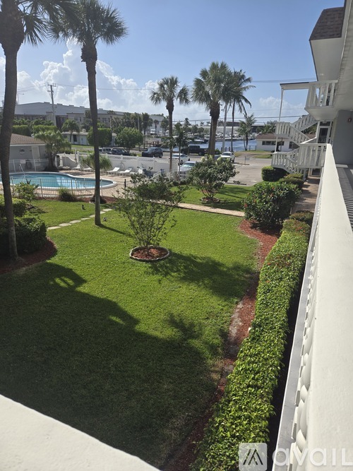 A view of a pool and palm trees from a balcony.