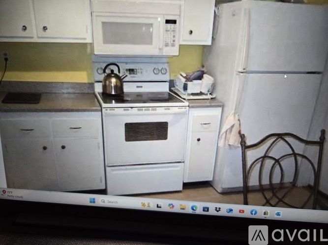 A white kitchen with a stove, microwave, and refrigerator.