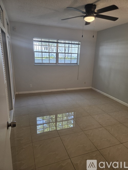 A room with a ceiling fan and a window with bars.