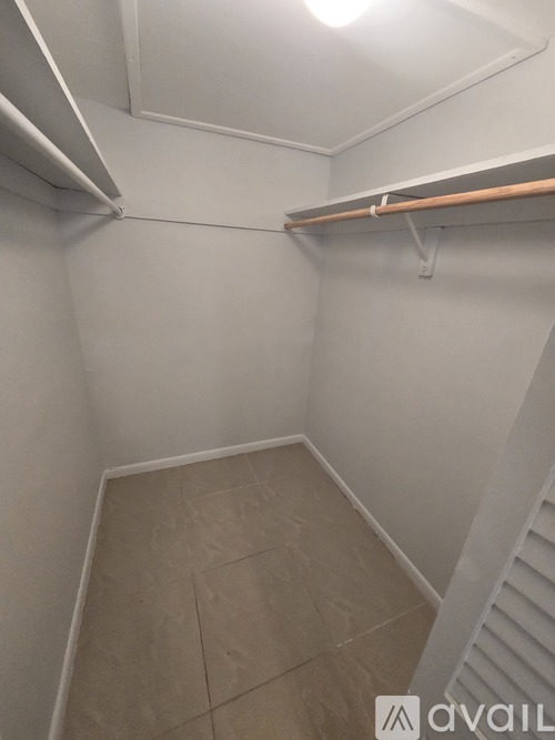 A small, empty room with a wooden shelf and tiled floor.