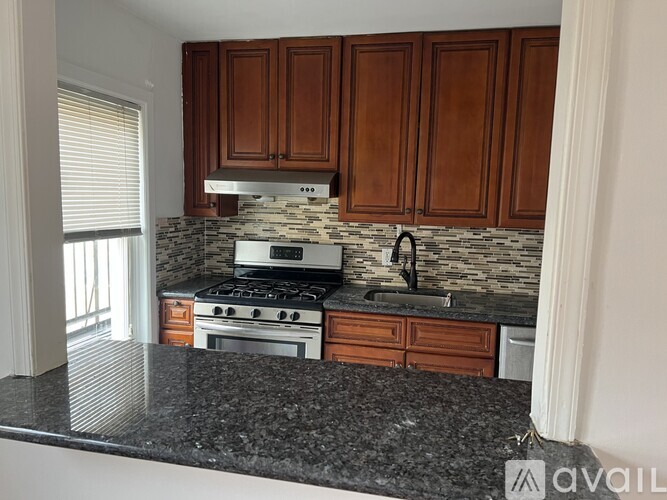 A kitchen with a granite countertop and wooden cabinets.