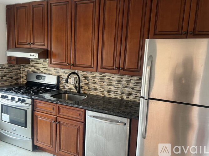A kitchen with wooden cabinets and a stainless steel refrigerator.