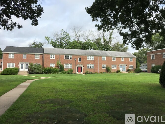 A building with a red door is surrounded by green grass.