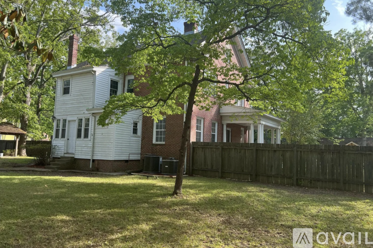 A white house with a brown fence and a tree in front.