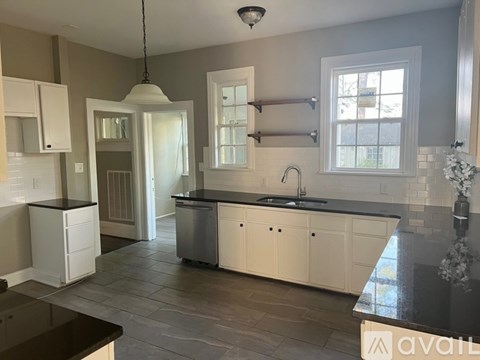 A kitchen with white cabinets and a black countertop.