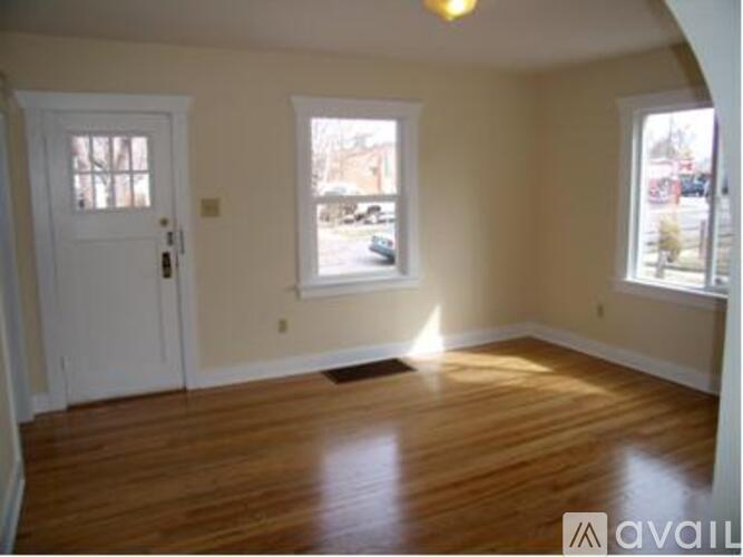 A room with wooden floors and two windows.