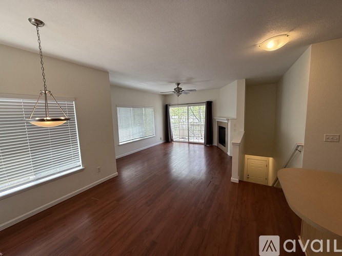 A spacious room with wooden floors and a hanging light fixture.
