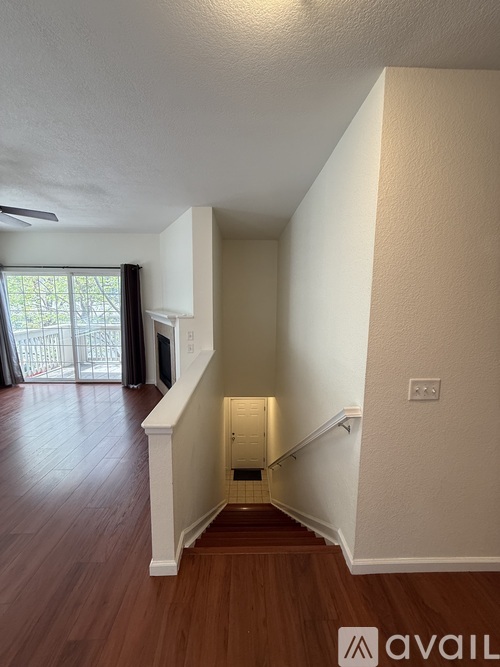 A hallway with wooden floors and white walls leading to a staircase.