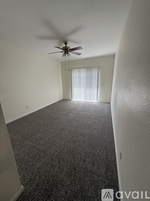 A room with a ceiling fan and carpeted floor.