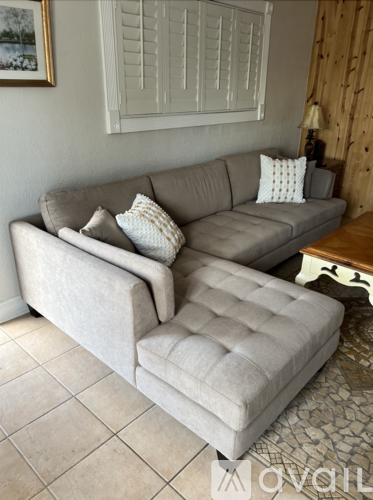 A grey couch with a white pillow and a white cushion on the floor.