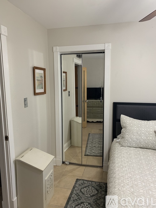 A bedroom with a bed, a nightstand, and a mirror.