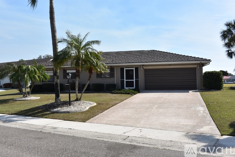 A house with a driveway and palm trees in front.