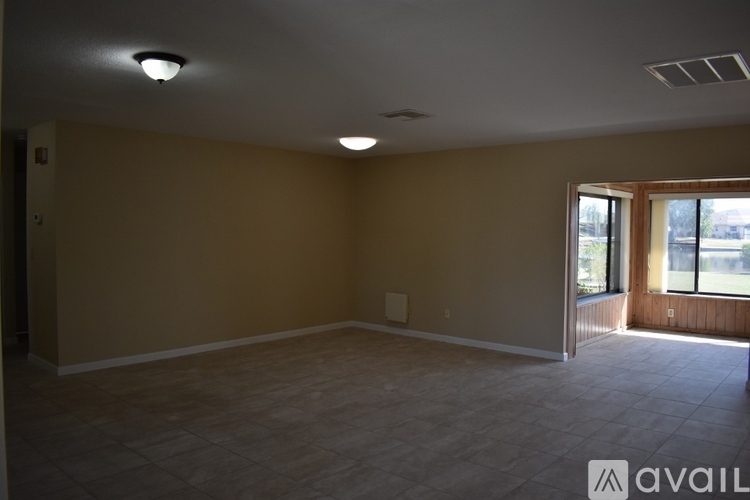 A spacious room with beige walls and a large window.