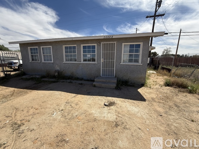 A small, single-story house with a fence in front is for sale.