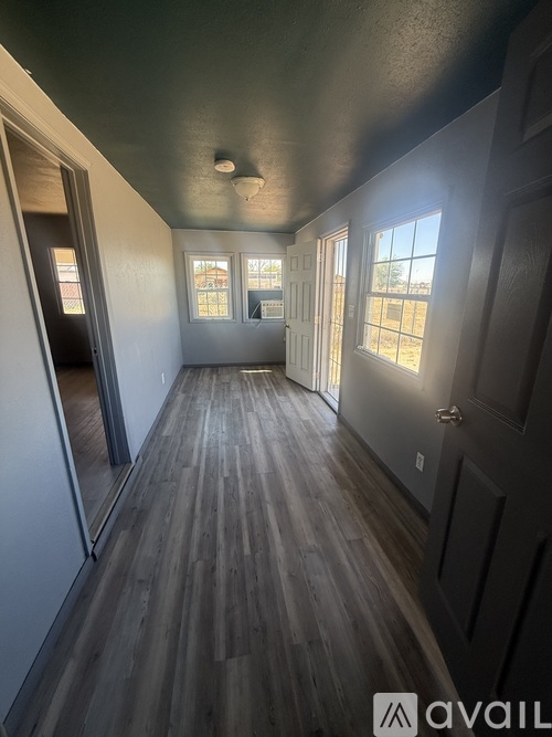 A long hallway with wood floors and windows on the side.