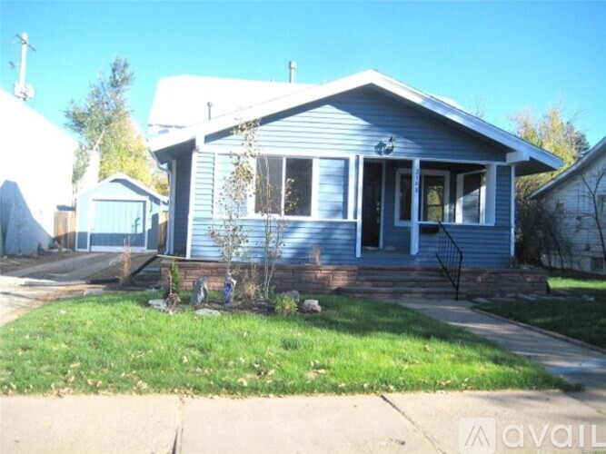 A blue house with a white fence and a small garden in front.
