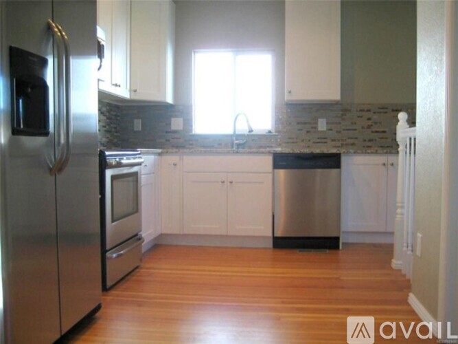 A kitchen with a stainless steel refrigerator and wooden floors.