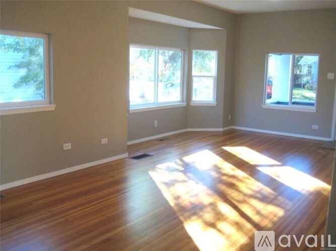 A room with wooden floors and three windows.