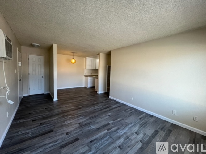 A spacious room with wooden flooring and white walls.