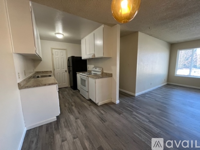 A kitchen with white cabinets and a black refrigerator.