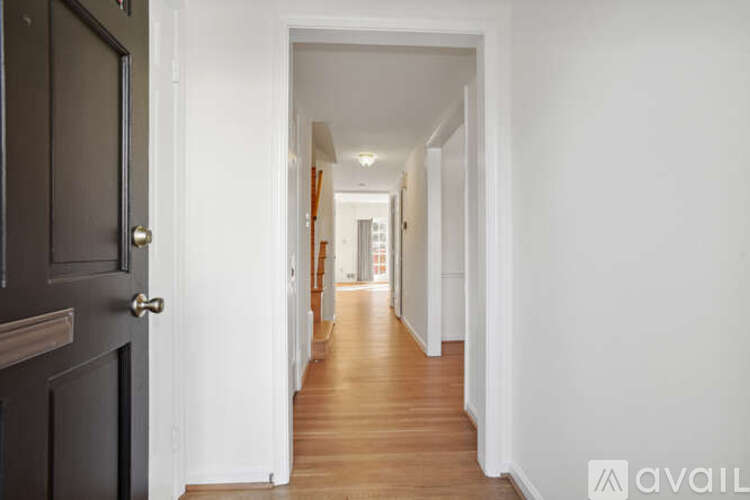 A long hallway with a black door on the left and white walls on the right.
