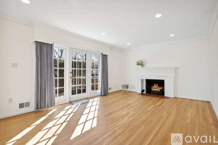 A spacious living room with a fireplace and a large window with curtains.
