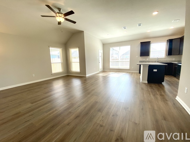 A spacious room with wooden flooring and a ceiling fan.