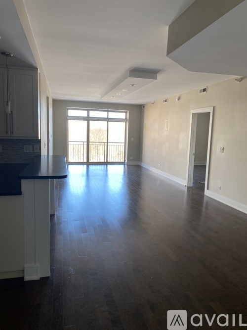 A spacious kitchen with dark wood floors and white cabinets.