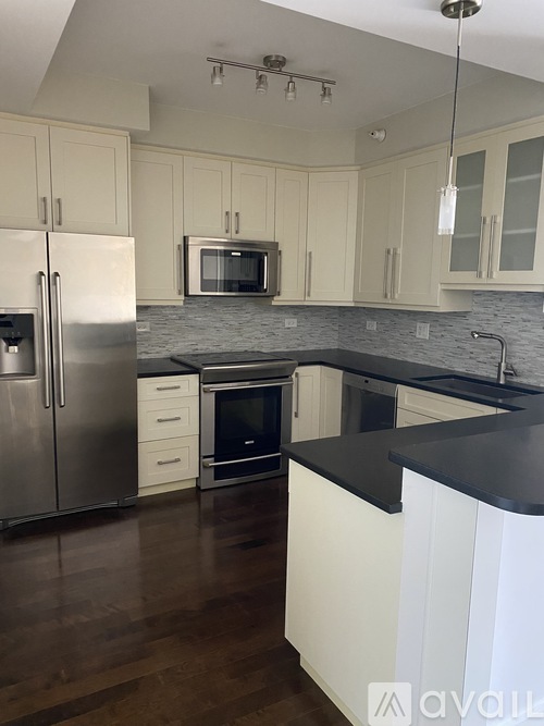 A kitchen with a black countertop and stainless steel appliances.