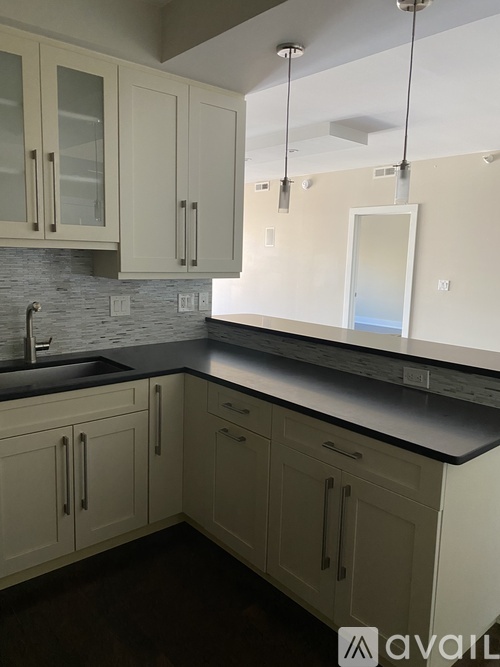 A kitchen with white cabinets and a black countertop.