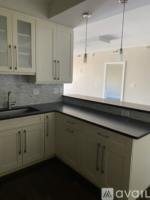 A kitchen with white cabinets and a black countertop.