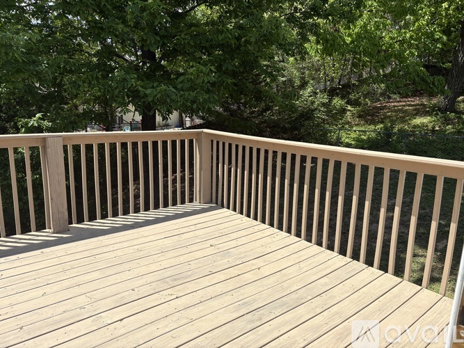 A wooden deck with a railing and trees in the background.