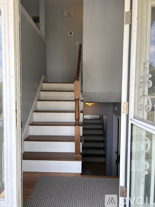 A staircase with a wooden handrail and white steps.
