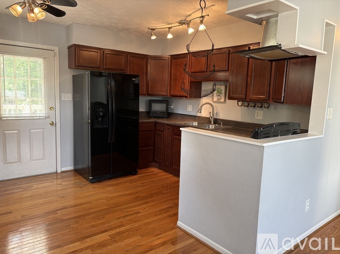 A kitchen with wooden cabinets and a black refrigerator.