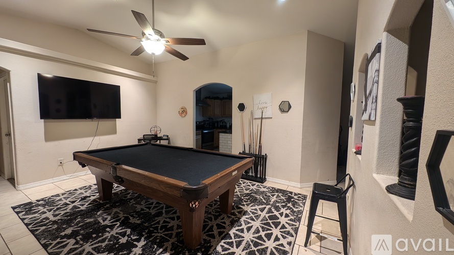 A pool table in a room with a ceiling fan and a television.