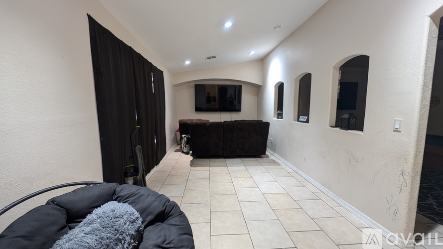 A living room with a black couch and a television.