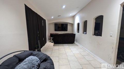 A living room with a black couch and a television.