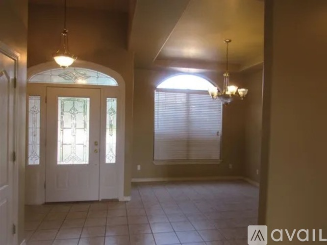 A hallway with a chandelier, a door, and a window with blinds.