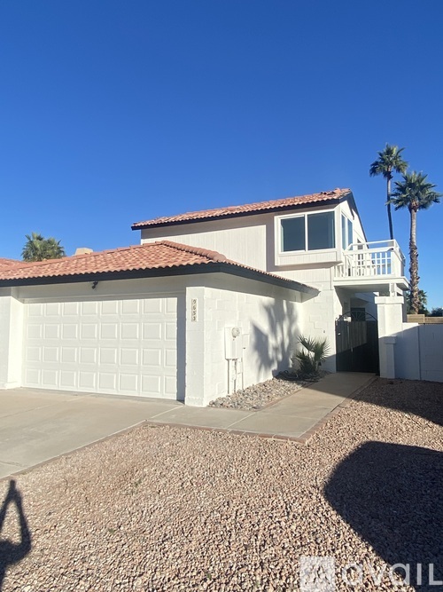 A house with a garage and a palm tree in front.